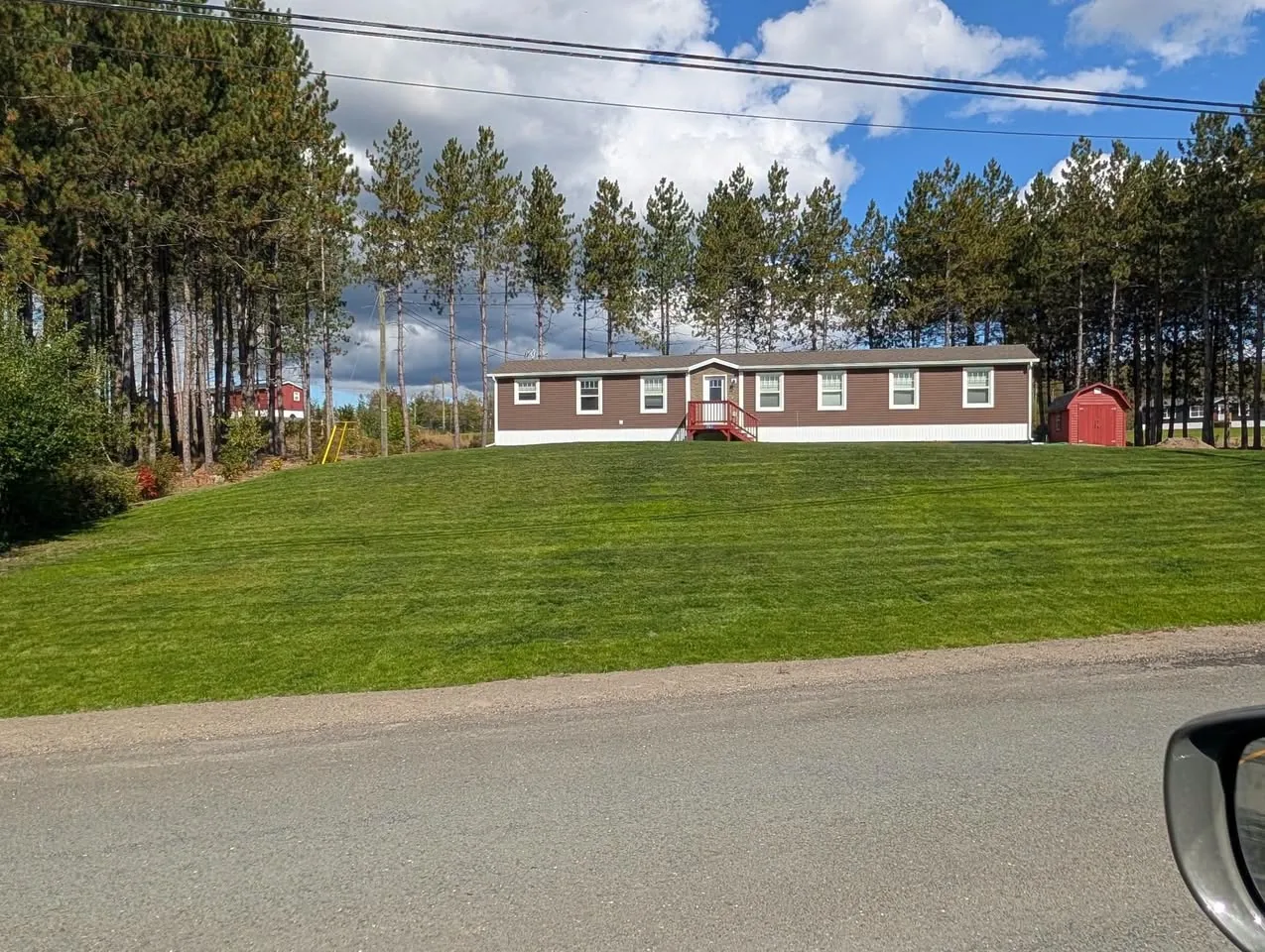 The same brown home with an established green front lawn and a gentler slope